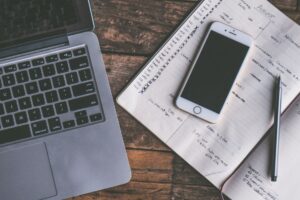 Birou cu laptop și carnet, în timpul redactării unei oferte de servicii
